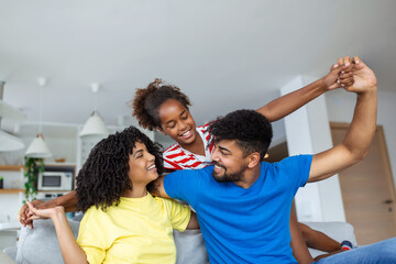 Happy family play together on couch at home.Mother father and child daughter enjoying happy relax spending time together in modern living room in evening.