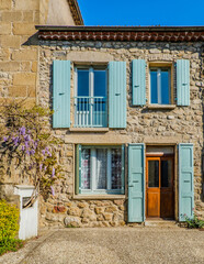 Fototapeta na wymiar facade of a beautiful stone house in Boucieu le Roi (Ardeche, France) with blue shutters