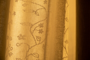 Curtain and mesh tulle with floral pattern in sunlight beams. Evening atmosphere. Atmospheric mood. Inspiration. Nobody. Living room interior decor. Cozy home details. Country or rustic design style