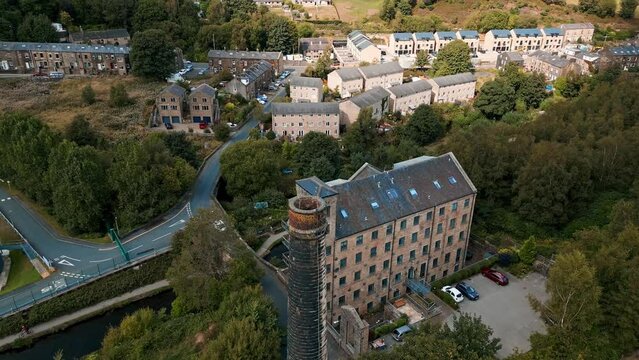 Drone footage of a old mill chimney stack, With footage rotating around the chimney and showing a canal and mill buildings. Shot in Hebden Bridge, Yorkshire, United Kingdom