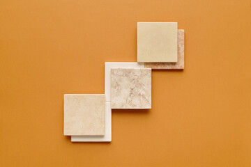 Horizontal top-down minimalistic flat lay composition of square ceramic tiles on light orange background