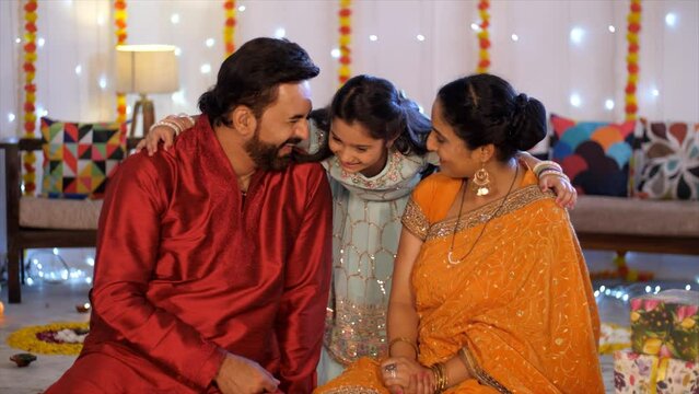 Happy Indian family - Young parents with cure daughter. Posing for the camera in the decorated house  Diwali get together. Small nuclear family in India during festival season - Young parents  Diwa...