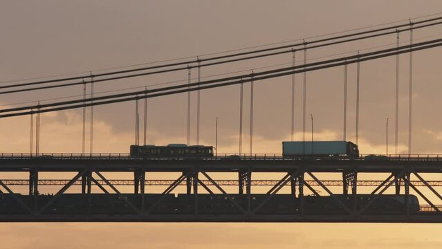 Ponte 25 de Abril Lisbon Portugal - 25 april Bridge, cars ant tracks moving over the bridge at sunrise Sunrise