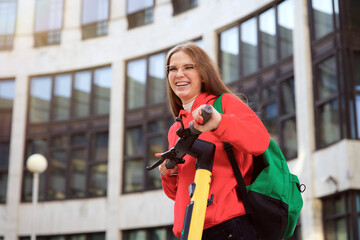 Young beautiful happy young woman, pretty attractive girl teenager university or college student is riding electro scooter at campus in the city smiling. Electric eco sharing transport © Евгений Шемякин