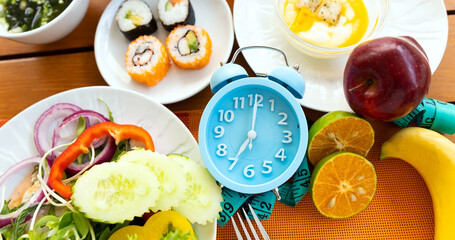 Blue alarm clock of a healthy food as Intermittent fasting with Time to lose weight , eating control or time to diet concept.