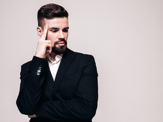 Portrait of handsome confident stylish hipster lambersexual model. Sexy modern man dressed in elegant black suit. Fashion male posing in studio. Isolated on grey