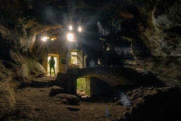Silhouette of a woman standing in the entrance of an abandoned troglodyte house in La Jaubernie, Ardeche (France)