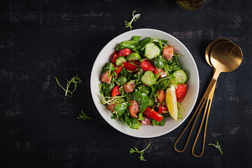 Ketogenic salad with salted salmon fish, lemon, cucumber, olives, tomatoes, green lettuce salad and honey mustard dressing. Healthy food trend. Top view
