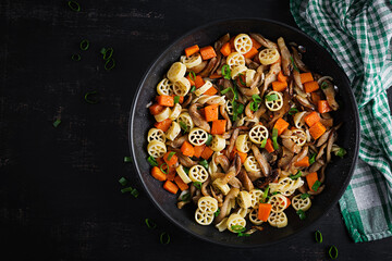 Rotelle pasta gluten free with mushrooms and pumpkin on a dark background. Vegetarian, vegan  food. Italian cuisine. Top view