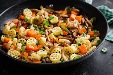 Rotelle pasta gluten free with mushrooms and pumpkin on a dark background. Vegetarian, vegan  food. Italian cuisine.
