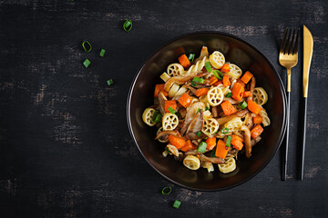 Rotelle pasta gluten free with mushrooms and pumpkin on a dark background. Vegetarian, vegan  food. Italian cuisine. Top view
