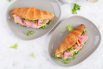 Fresh croissant or sandwich with salad, ham and cheese on light  background. Top view