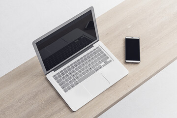 Close up of empty laptop and mobile phone on wooden desktop, mock up place on screen, concrete flooring background. 3D Rendering.