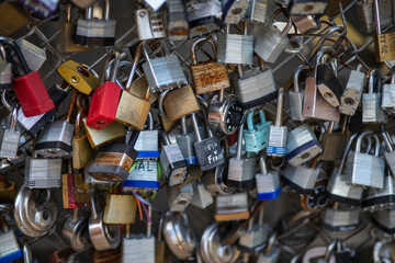 Old and new padlocks with names and dates written on them lock on a bridge as a sign of love in San Antonio, Texas.