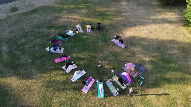 Editorial Use Footage. Group of English Women doing Yoga Exercise with a lady instructor at Local Public Park of Luton Town of England UK on a hot summer day at sunset time	