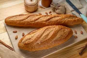 Baked baguette and multigrain loaf bread on brown wooden table ready to serve.