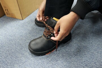 A male worker is tying his shoes to get ready for work