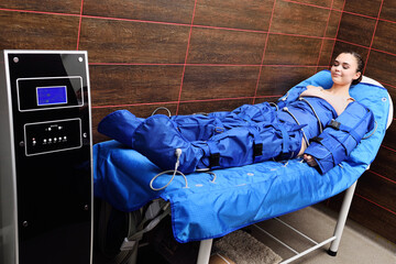 young pretty woman on the procedure of pressotherapy - hardware massage using compressed air.
