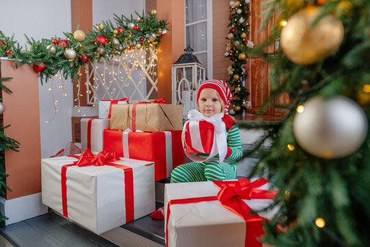 Child Sitting In Front Of The Door With Many Christmas Gift Boxes