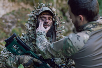 A military man or airsoft player in a camouflage suit sneaking the river and aims from a sniper rifle to the side or to target.