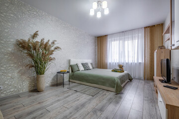 interior of the modern luxure bedroom in studio apartments in light color style with pillows and towels