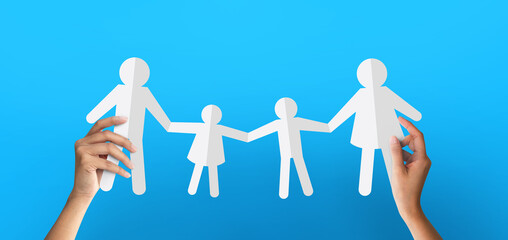 Hand holding paper chain group family at blue background. family concept.