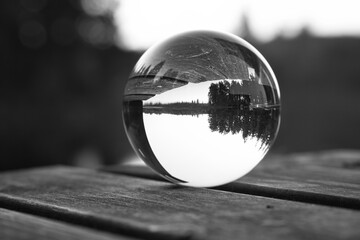 Glass ball on a wooden pier at a Swedish lake at dusk in black and white. Nature