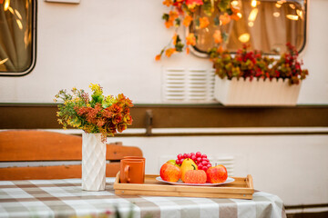 Decorative Apples, pears and grapes lie in a plate on the table against the background of the trailer