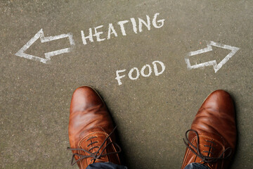 Person having to decide between Heating and Food - top view of the words and arrows pointing in opposite directions
