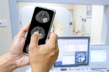 The doctor is using a cell phone to check the patient's brain MRI results. The background is an electromagnetic control room. medical technology concept