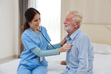 Happy caregiver examining senior elderly man patient listening heartbeat using stethoscope on bed...