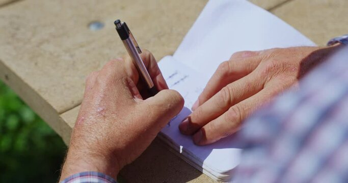 Left-handed Man Writing On His Notebook With A Pen on The Wooden Table. - close up