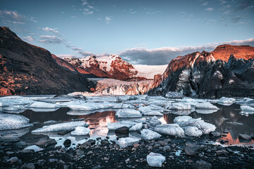 Warm sunlight across the ice and mountains of Svinafellsjokul glacier at sunset, southern iceland. Part of the larger Vatnajokull glacier, the largest ice cap in iceland. Dark and moody style.