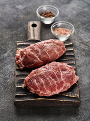 Fresh raw pork cheeks with salt and pepper. Grey background