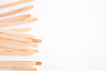 Materials for depilation of eyebrows and delicate areas. Wooden sticks lie on a white background - obrazy, fototapety, plakaty