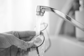 Personne qui lave ses lunettes de vue à l'eau claire du robinet