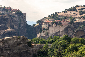 Fototapeta na wymiar View from main observation point of Meteora over the hills and cliffs with Holy Monasteries of Varlaam on the right and Great Meteoron on the upper left, Kalambaka, Central Greece