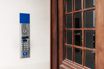 Modern intercom on white wall near door outdoors