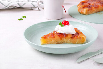 Sweet pie with caramelized banana served in piece with whipped cream and cherry on green plate. Homemade dessert