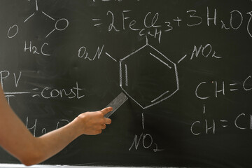 female teacher explane chemical formulas near chalkboard