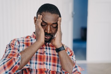Tired upset african american man suffer headache with his head in his hands. Stress at work, burnout
