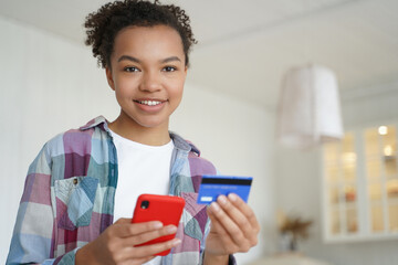 Smiling mixed race girl holding bank credit card, use online banking services, e-bank mobile apps
