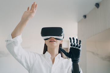 Disabled girl in vr glasses testing new bionic prosthetic arm. Rehabilitation after limb loss