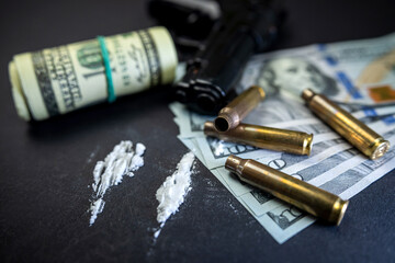 Cocaine in bags next to dollars and a gun isolated on black background.
