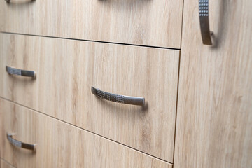 closeup of natural wooden wardrobe drawer front with handle