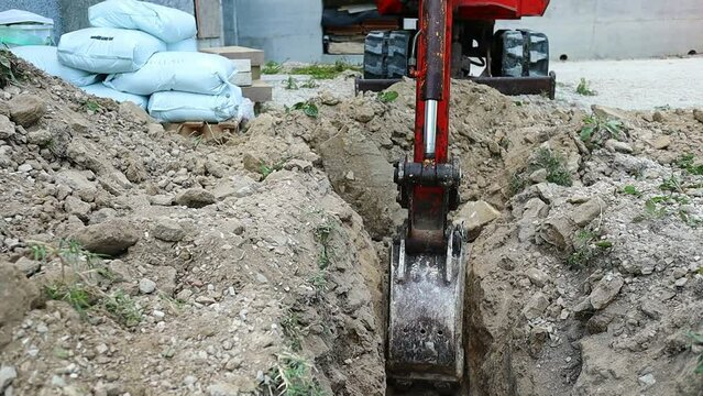 small digger lifts a large stone from the excavation