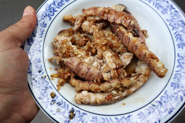 Hand holding stir-fried giant crayfish with garlic and pepper. Deep fried crayfish in Thai style. Popular Thai seafood recipe.  