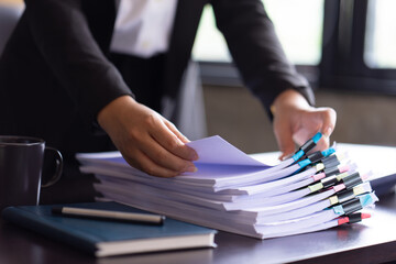 Asian businesswoman standing at her workplace and checking financial documents.