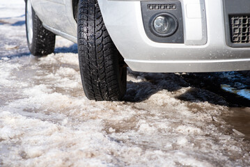 Close-up shot of a car moving on icy countryside road. Road in terrible condition