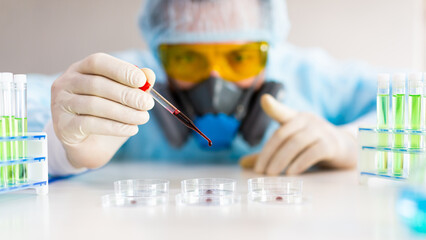 Researcher dripping a blood sample in a Petri dish. Focus on a pipette.